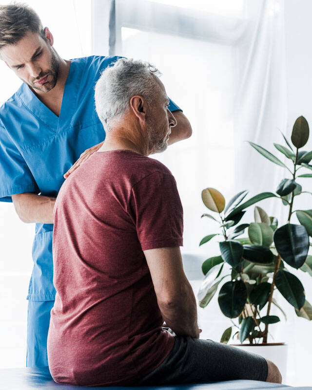 Male chiropractor in Denver examining patient