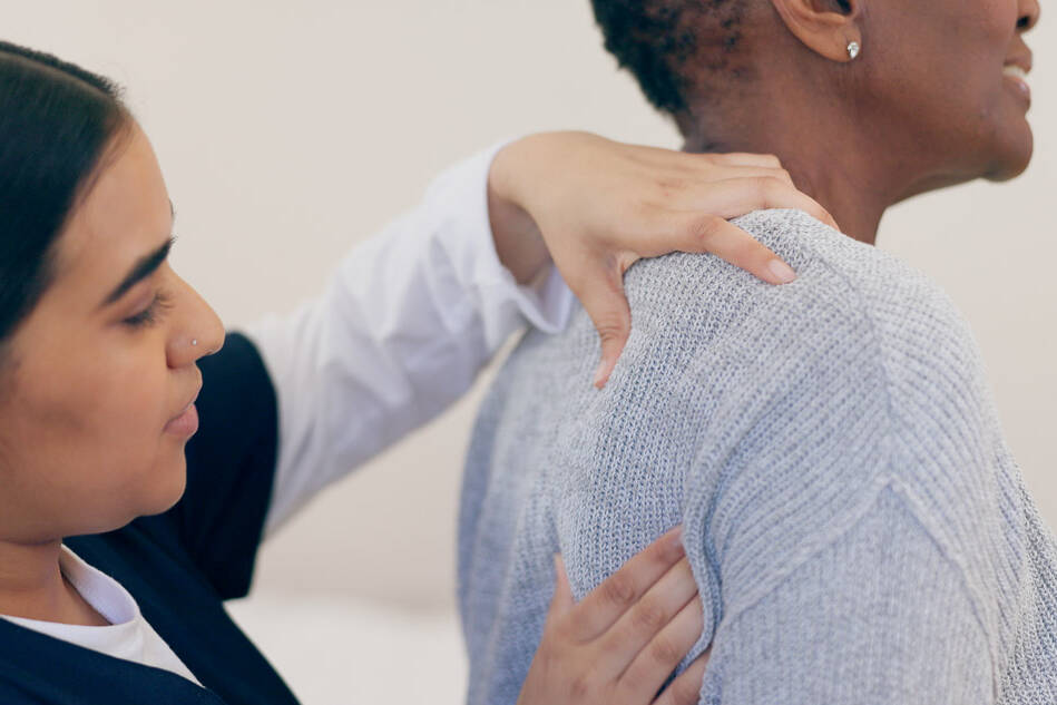 Female chropractor in Denver examining a shoulder